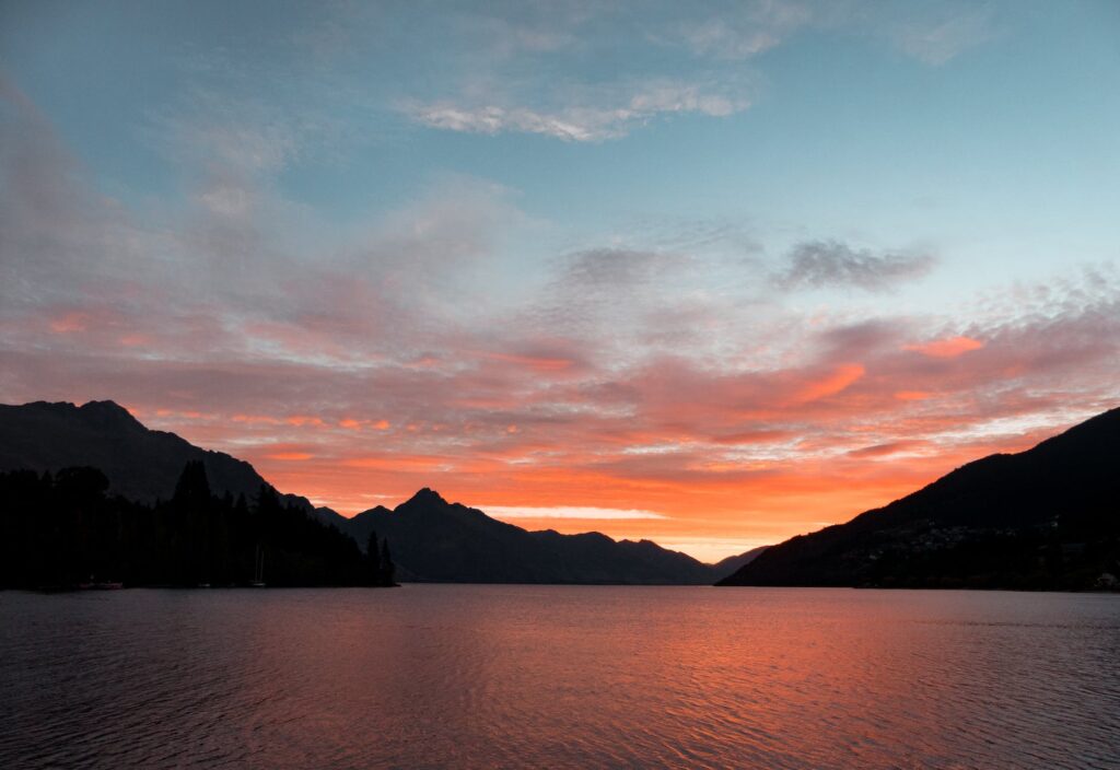 Sacral Chakra body of water near silhouette of mountain under white clouds during sunset