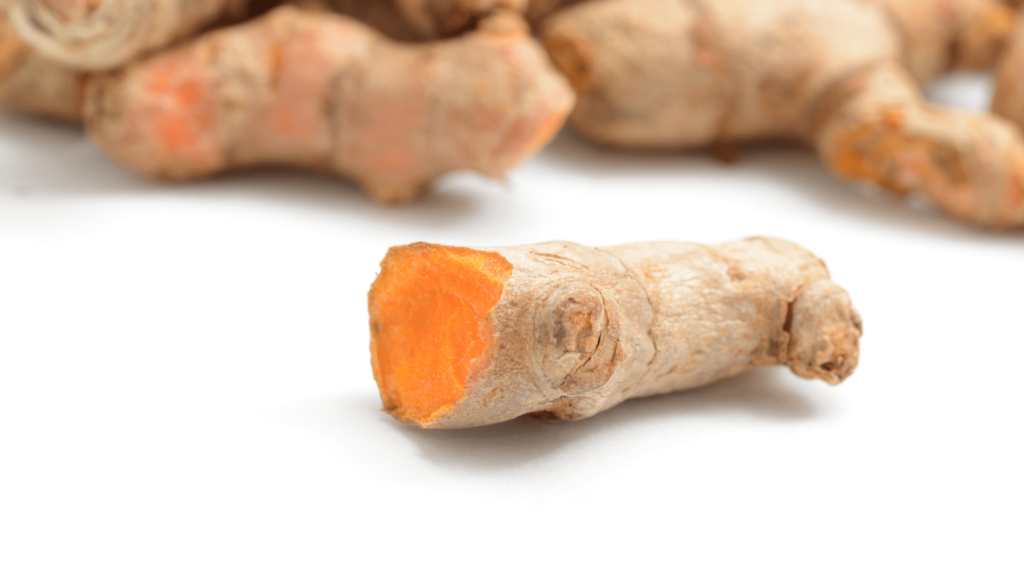 An illustrative image of vibrant turmeric root rhizome cut on a white background