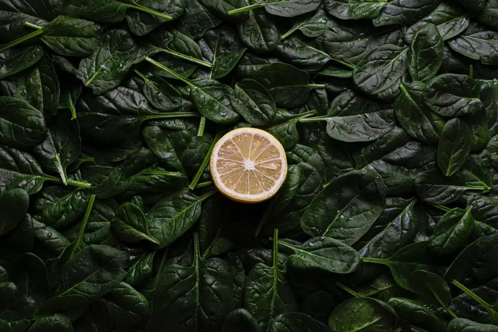 A Sliced Lemon Fruit on Green Spinach Leaves