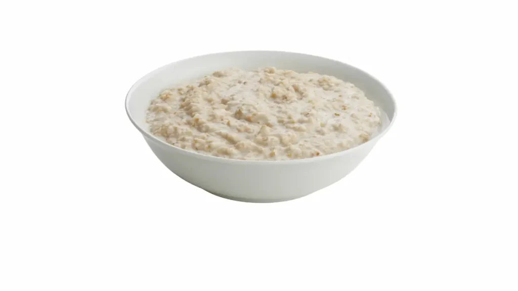 A bowl of cooked organic oats in a white bowl on a white background