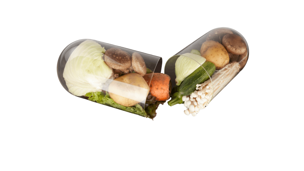 An illustrative image of a clear, half-open capsule with vegetables on a white background.